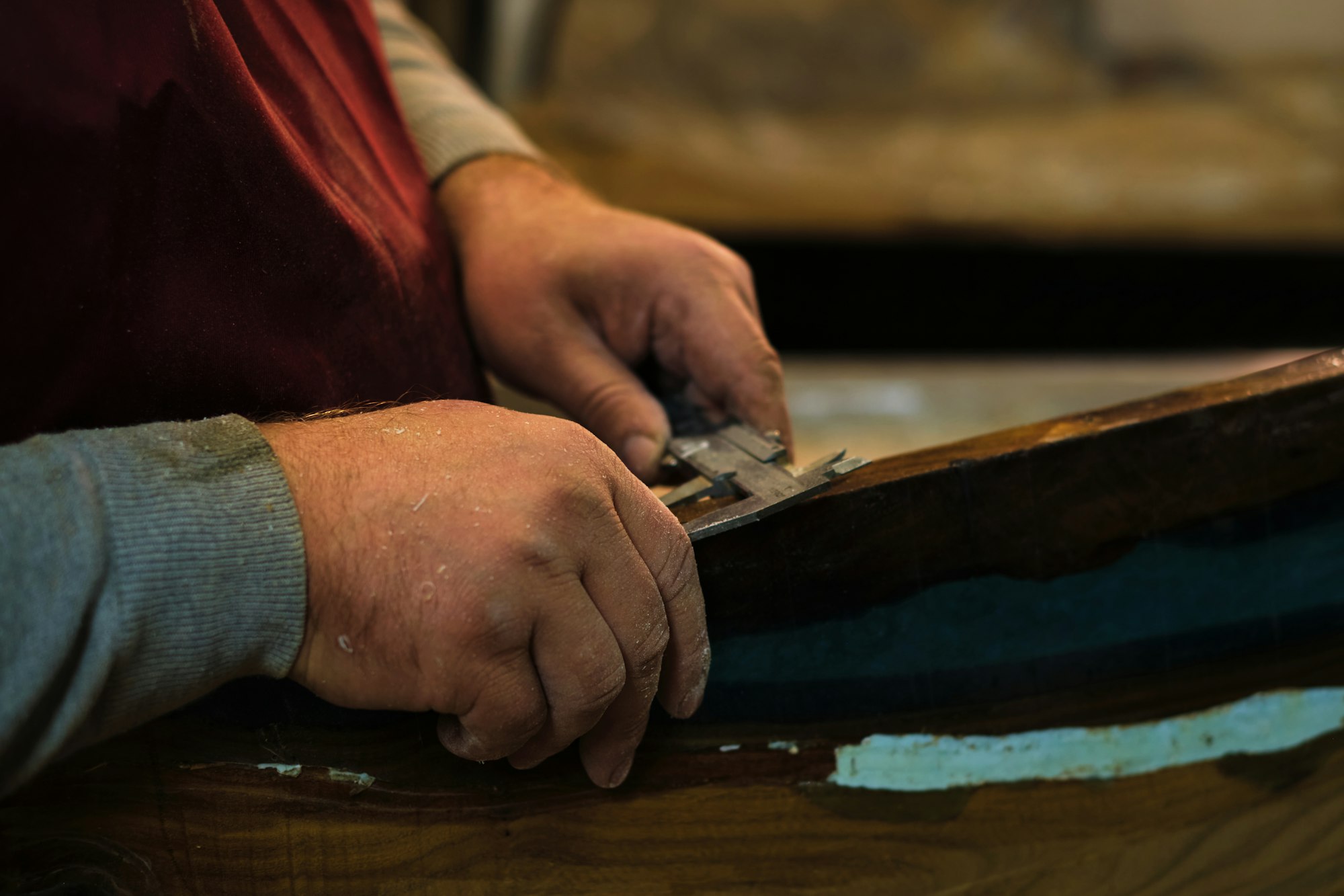Artisan measuring with a tool; dedication, skill. Emphasizes the resurgence of traditional